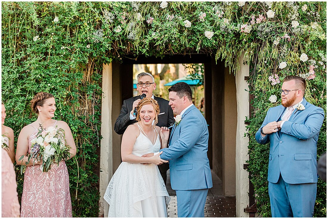 Bride and Groom standing under greenery arch at the end of the aisle at Hacienda Del Sol