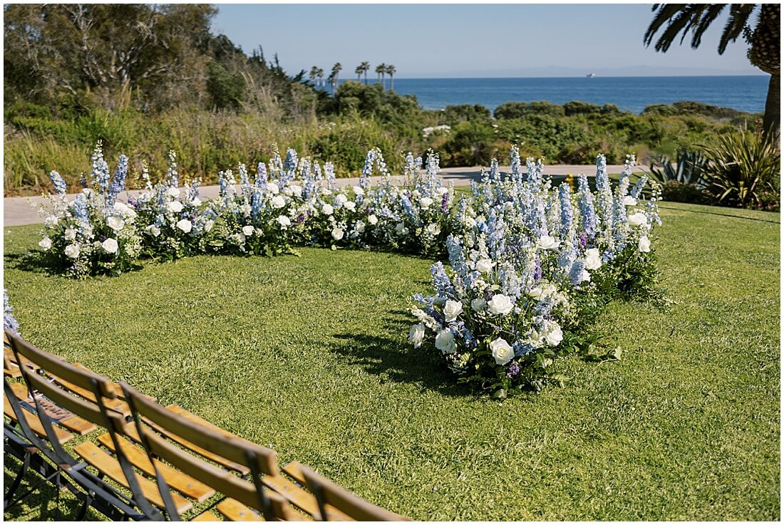 Wedding set up on the event lawn at the ritz carlton bacara in santa barbara with blue flowers, white roses, and a view of the ocean