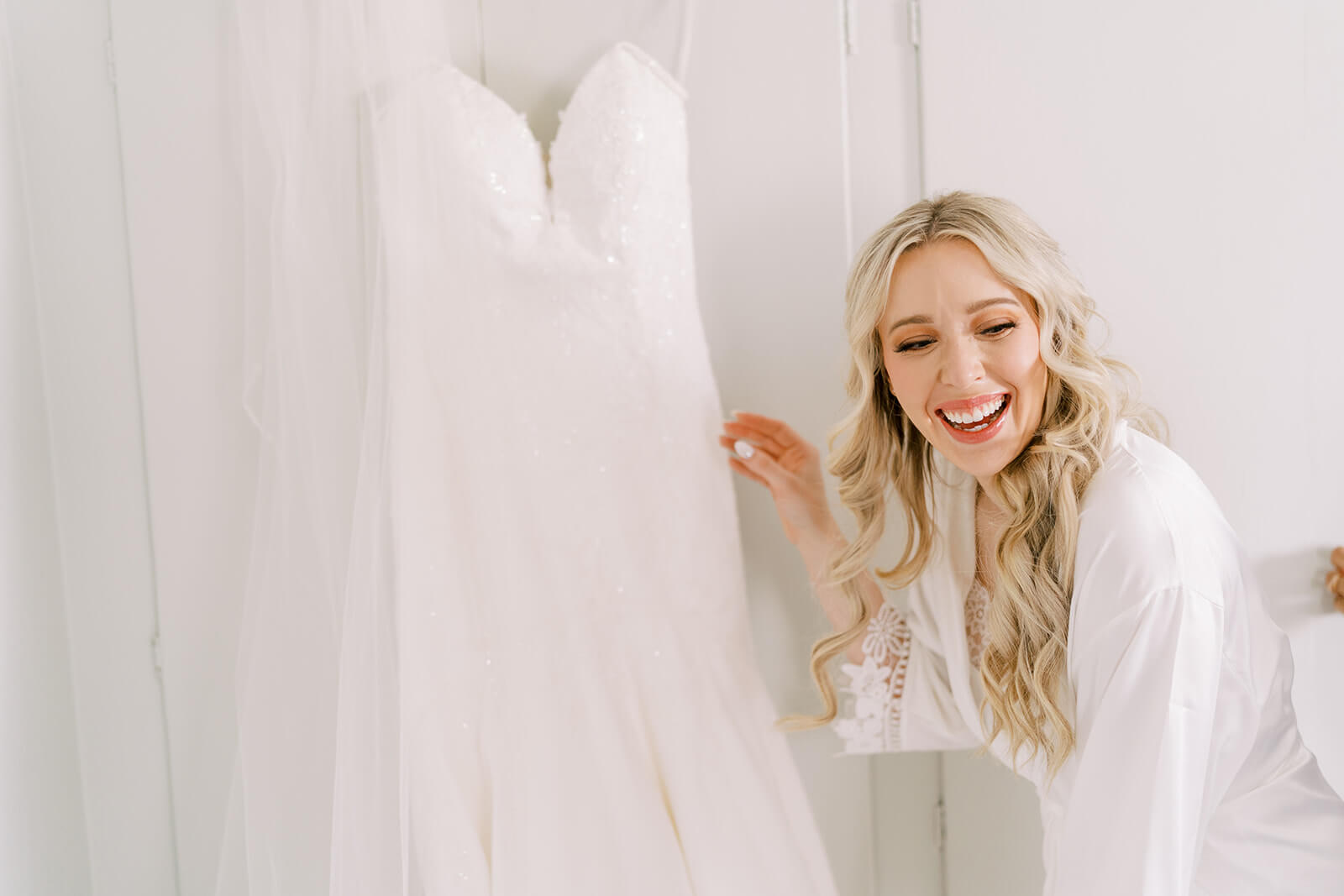 bride laughing next to her wedding gown if it gets a stain the bridal emergency kit could help get out 